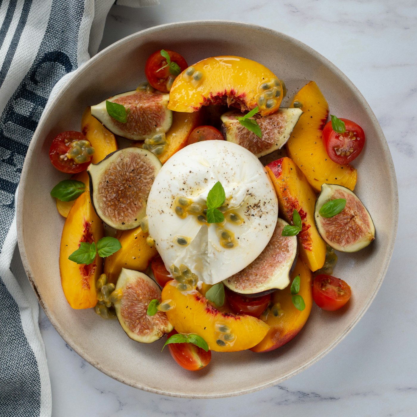 Burrata with peaches and figs on a white plate