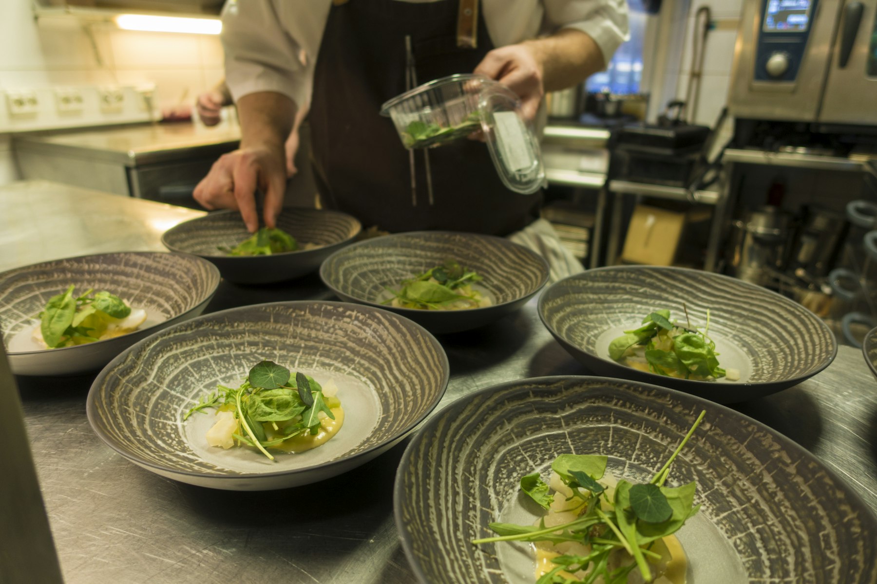 Bowls being plated on the pass of the kitchen
