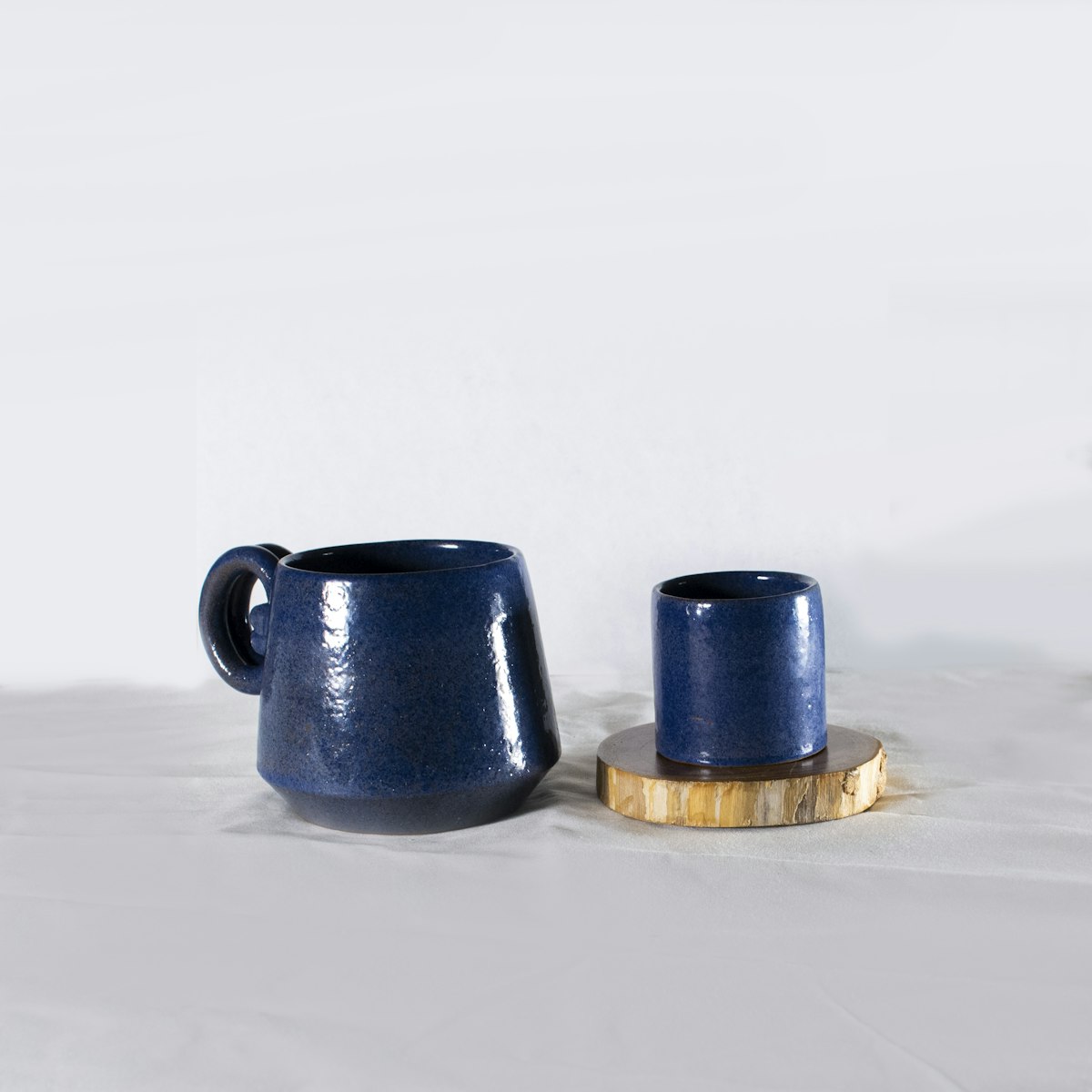 Two deep blue mugs on a white table
