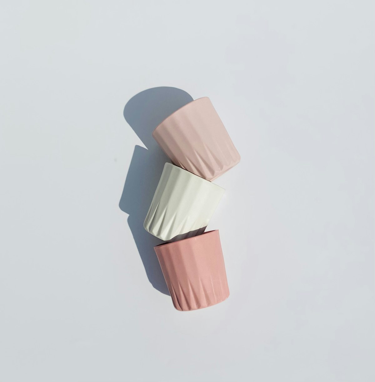 Three fluted cups, stacked, in pink and white